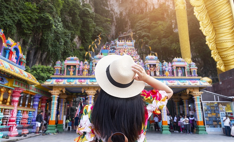 Templo colorido na Malásia contemplado por mulher viajante