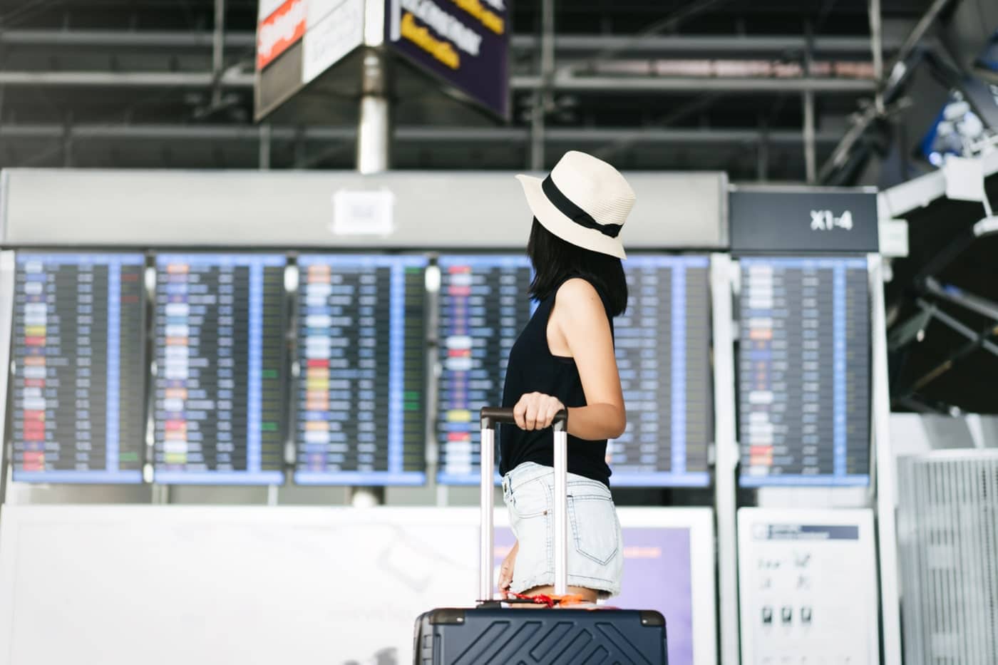 Mulher acompanhando os cancelamentos de viagens no painel do aeroporto