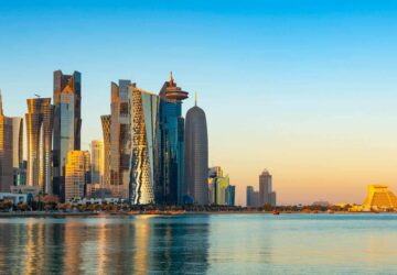 Sol nasce na cidade de Doha e prédios refletem sobre as águas