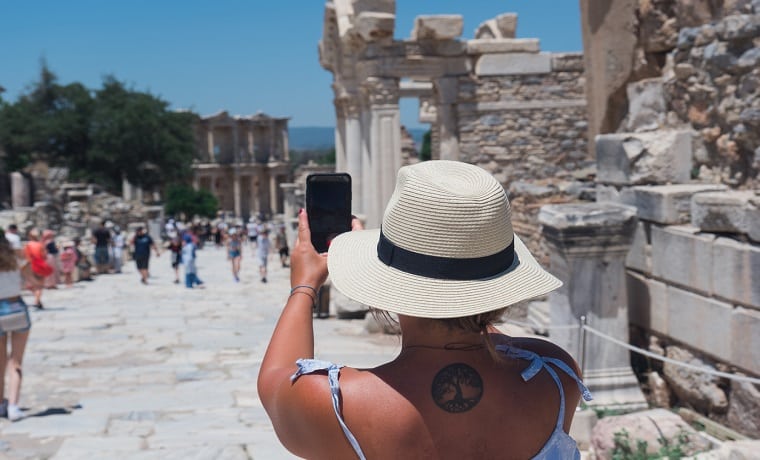 Mulher com tatuagem nas costas tirando foto de um ponto turístico