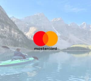 Lago Moraine com mulher passeando no caiaque, com logo Mastercard Seguro Viagem em primeiro plano
