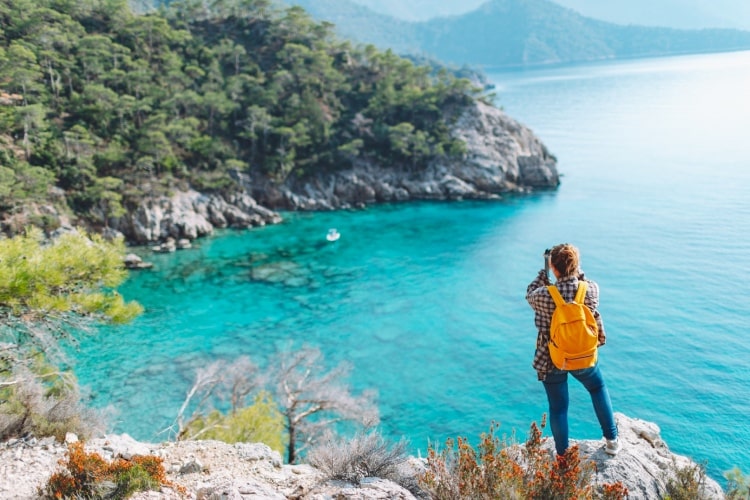 Turista fotografa uma praia com mar azul turquesa