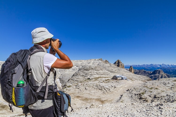 Homem fotografando uma vista em viagem, no topo de uma montanha. Homem em viagem, tirando foto de vista.