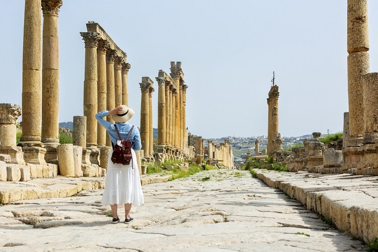 Mulher turista olhando uma vista de pilastras em ruínas.
