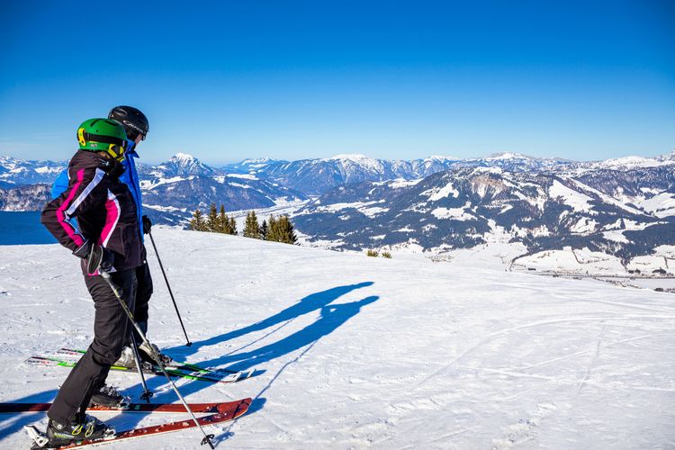 Casal de esquiadores admirando a vista tranquilamente, após contratar seguro viagem esquiar. 