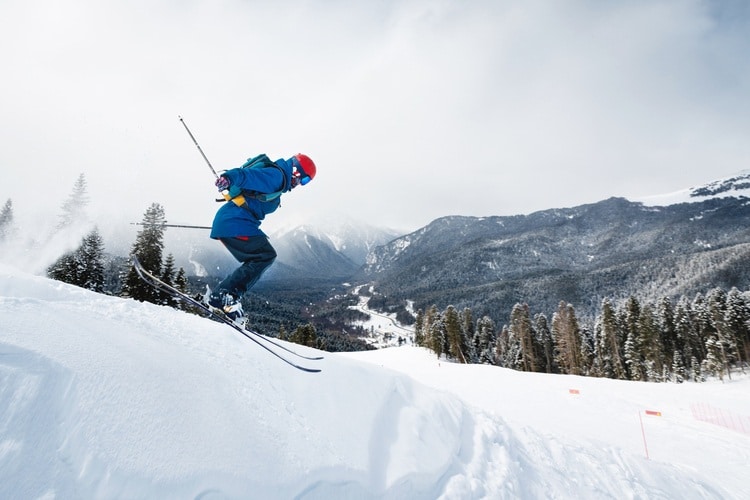 Homem saltando enquanto esquia na montanha.