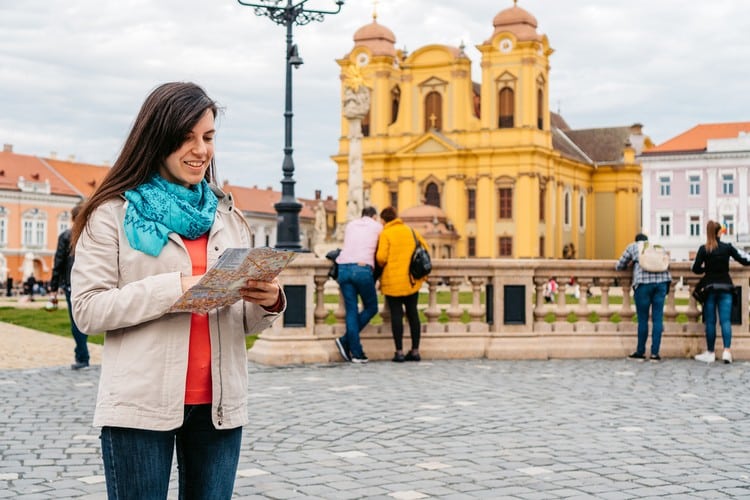 Mulher olhando o mapa enquanto passeia por uma cidade histórica. 