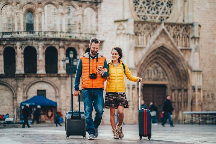 Homem e mulher caminhando com malas pela Europa e entrando em contato com a Safety Card seguro viagem. 
