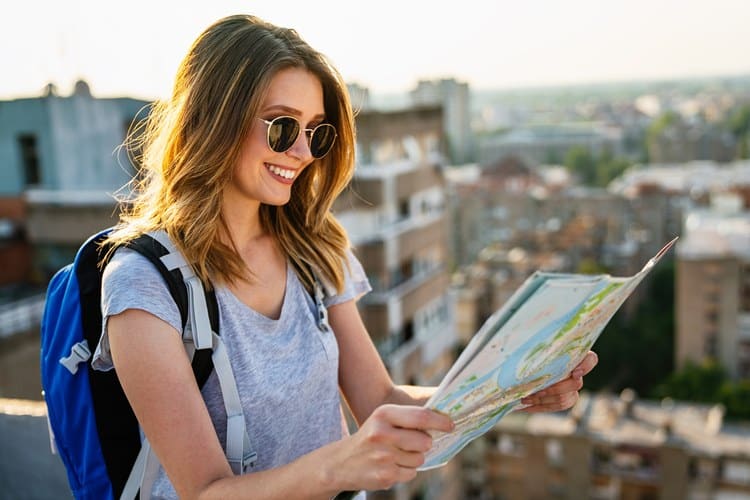 Mulher viajante sorrindo ao ler o mapa do país. 