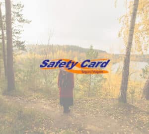 Mulher em floresta durante o outono. Em primeiro plano logo da Safety Card Seguro Viagem