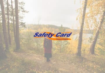 Mulher em floresta durante o outono. Em primeiro plano logo da Safety Card Seguro Viagem