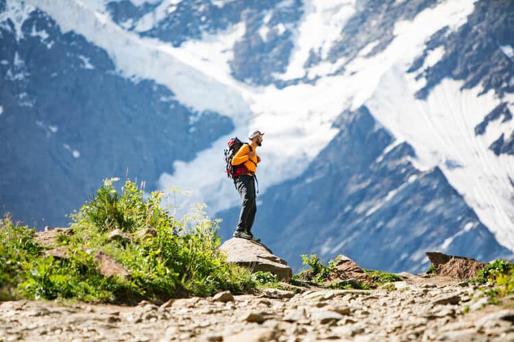 Homem em pé, em frente a montanha com gelo.