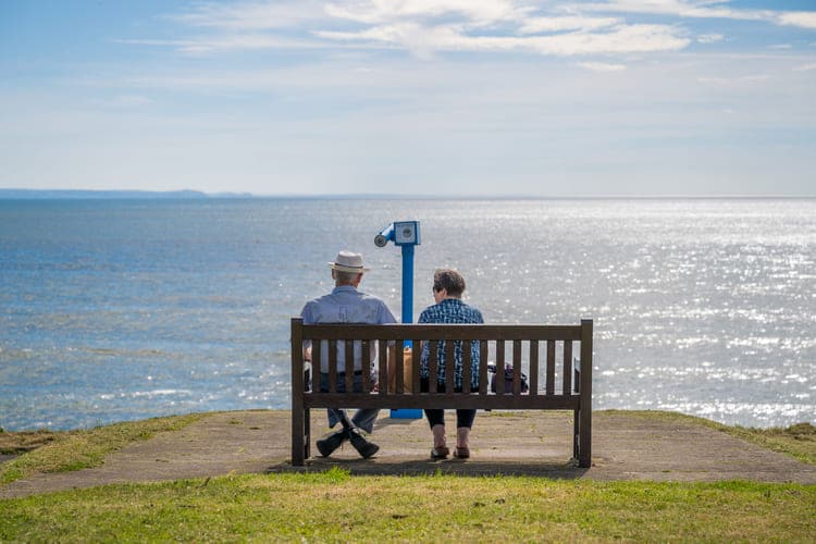 Homem e mulher admirando a paisagem sentados em banco
