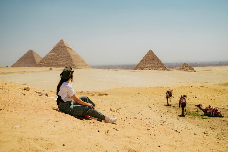 Mulher sentada olhando pirâmides.