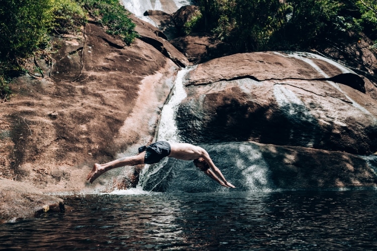 Homem nadando em uma cachoeira.