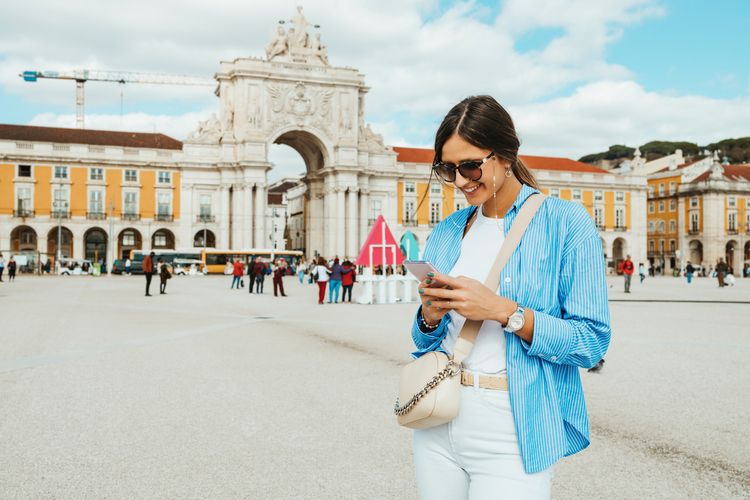 Viajante em Portugal entrando em contato com a Affinity Seguro Viagem pelo celular. 