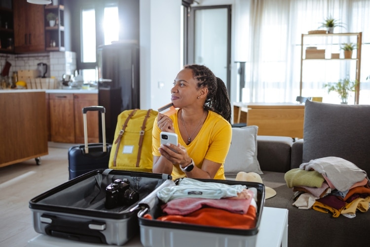 Mulher organiza a mala e compra seguro viagem online