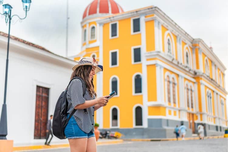 Viajante explorando a cidade e acessando o seu seguro viagem Sulamérica pelo celular.