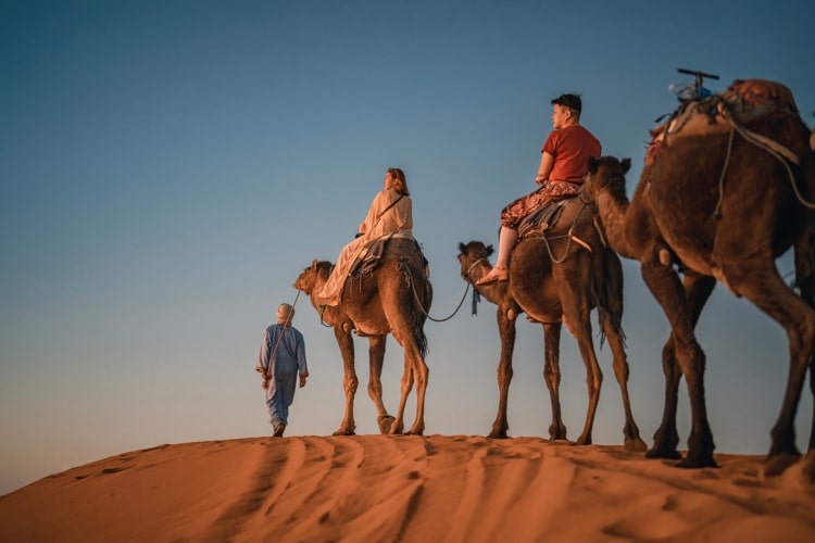 Turistas em passeio de camelo no deserto