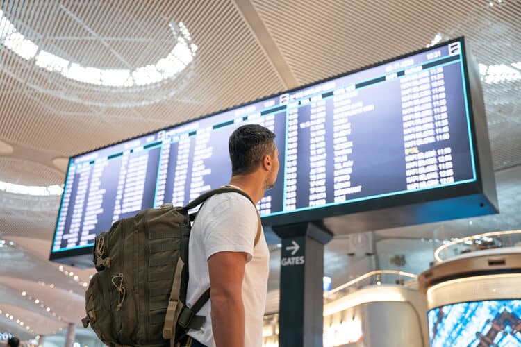 Homem olhando horário de voos em aeroporto