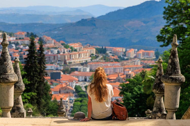 Pessoa branca de costas admirando paisagem de cidade em Portugal