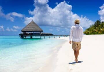 Turista com seguro viagem Maldivas caminhando por uma das ilhas da região