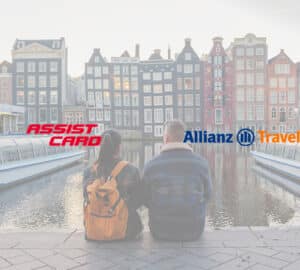 Casal de turista aprecia a vista do canal de Amsterdam. Em primeiro plano, logo Assist Card e Allianz Travel