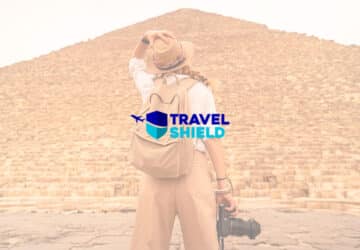 Mulher em frente a pirâmide do Egito. Em primeiro plano, logo Travel Shield
