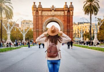 Turista com seguro viagem Espanha diante do Arco do Triunfo em Barcelona.