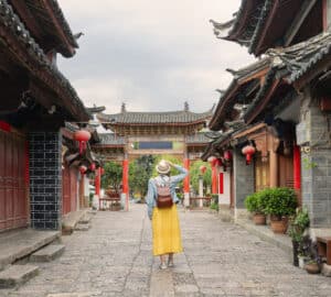Turista explorando a cidade antiga de Lijiang, na China, ilustrando a importância de contratar o melhor seguro viagem para destinos internacionais